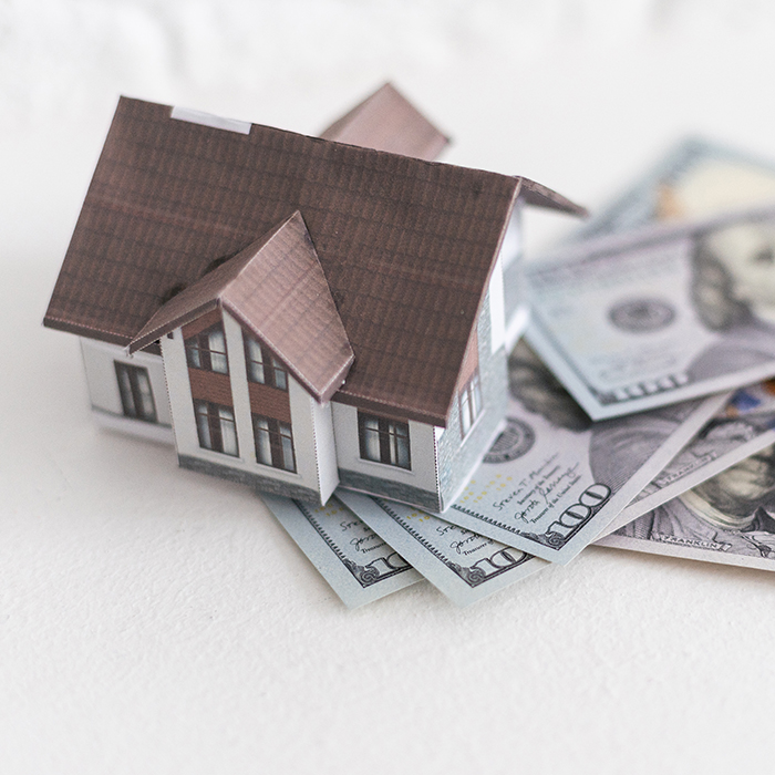 house-standing-on-a-pile-of-dollar-bills-investment | Honor Home Loans