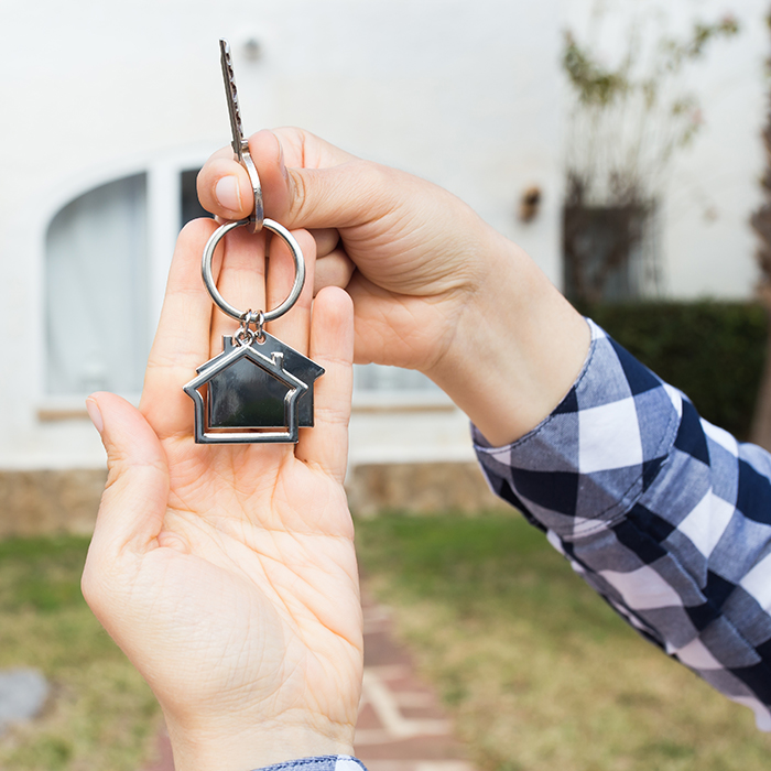 two hands holding keys in front of a new home | Mortgage with Honor